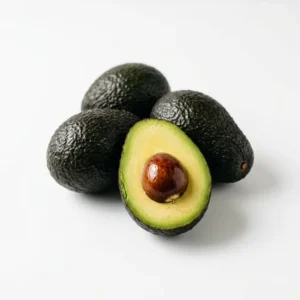 Three whole Hass avocados and one halved showing buttery green-gold flesh